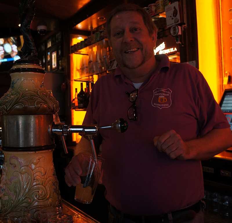 Barman achter de tap van Café Corso