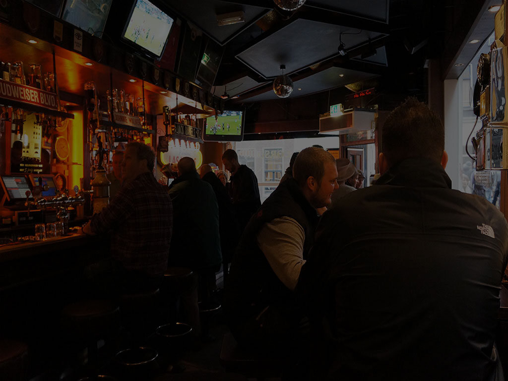 De lange bar van Café Corso met barkrukken en schermen